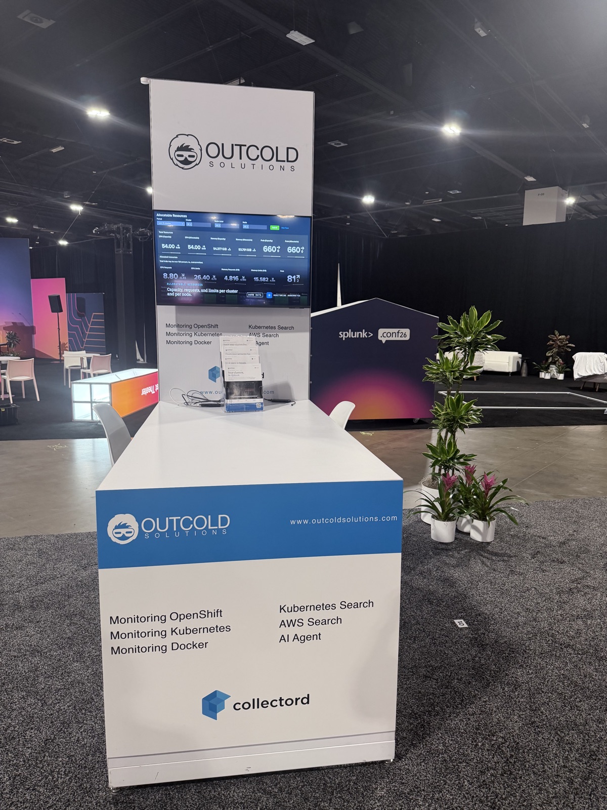 The Outcold Solutions booth at .conf26 with the Monitoring Kubernetes capacity dashboard on screen