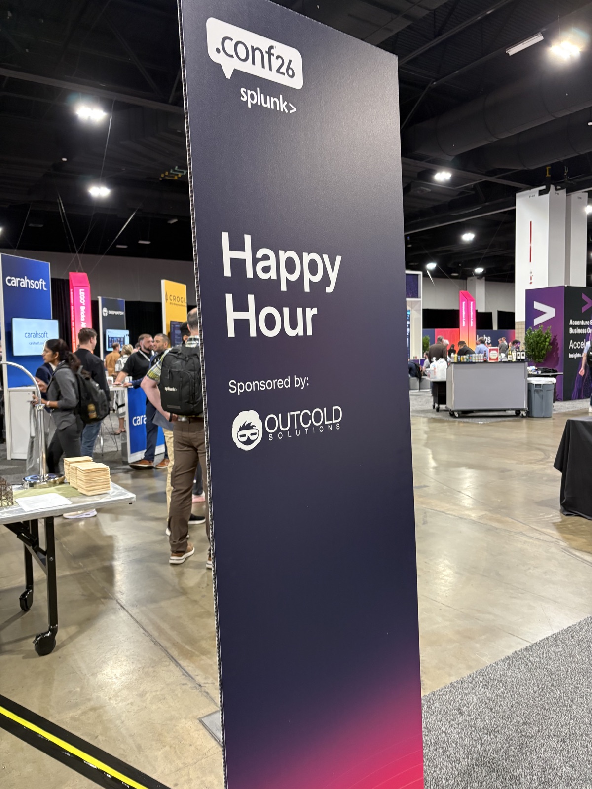 The .conf26 happy hour sign on the expo floor, sponsored by Outcold Solutions